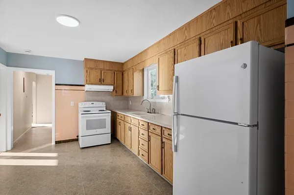a kitchen with a refrigerator a stove top oven and cabinets