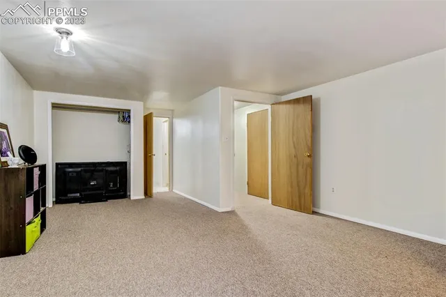 a view of an empty room with a fireplace and a chandelier fan