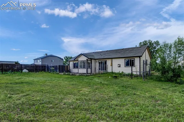 a view of a big house with a big yard and large trees