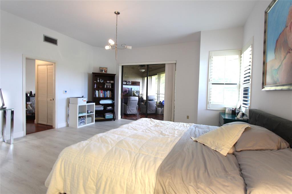 7535 La Paz Boulevard, Unit 301 Boca Raton, FL 33433 - Photo 17 of 42 a spacious bedroom with a bed and a large mirror with a chandelier