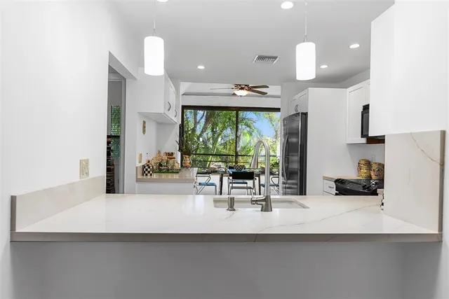 a kitchen with a sink a counter top space and living room view
