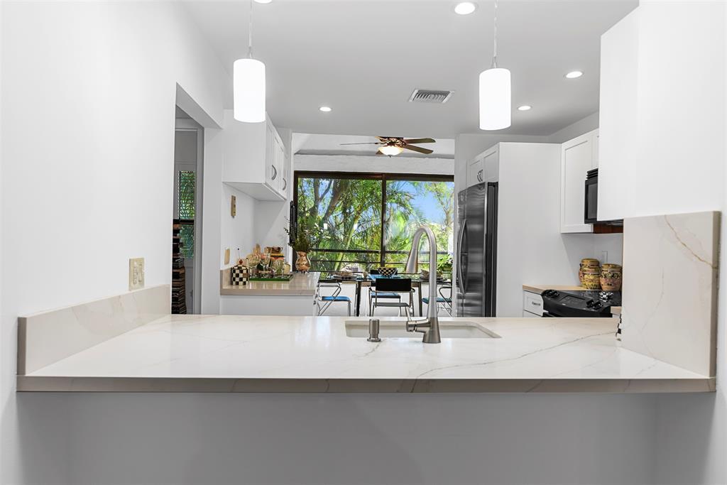 7535 La Paz Boulevard, Unit 301 Boca Raton, FL 33433 - Photo 5 of 42 a kitchen with a sink a counter top space and living room view