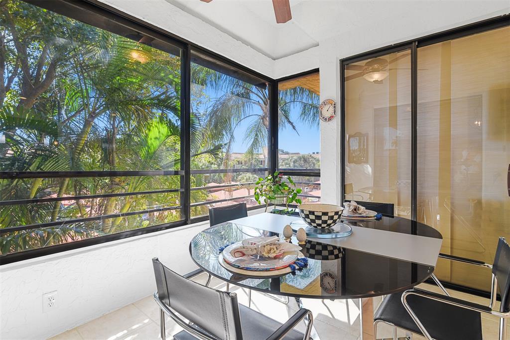 7535 La Paz Boulevard, Unit 301 Boca Raton, FL 33433 - Photo 7 of 42 a dining room with furniture a flat screen tv and a floor to ceiling window