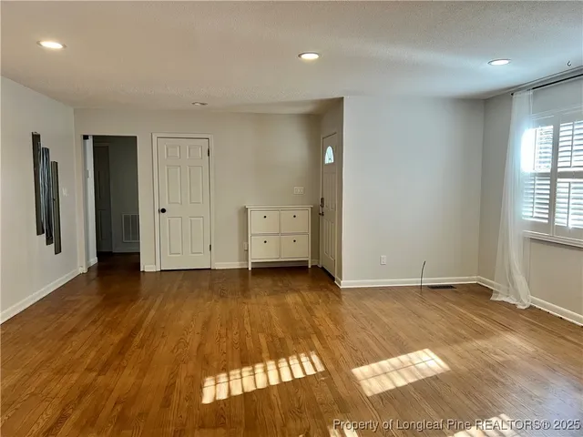 a view of an empty room with window and wooden floor