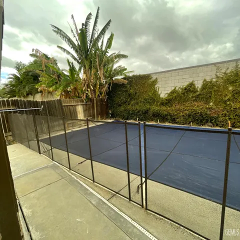 a view of a backyard with table and chairs potted plants and large tree