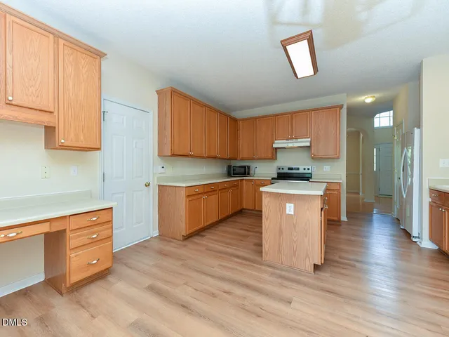 a kitchen with stainless steel appliances kitchen island granite countertop a stove a sink and a refrigerator