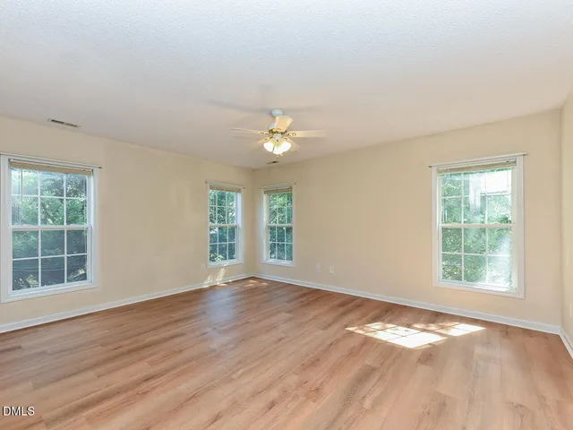 an empty room with wooden floor and windows