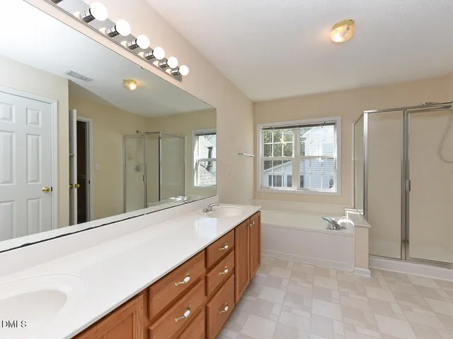 a spacious bathroom with a granite countertop double vanity sink a mirror and a bathtub