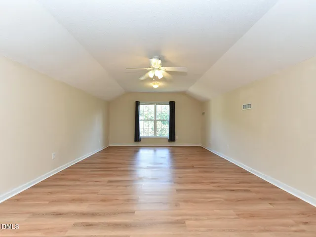 a view of an empty room with window and wooden floor