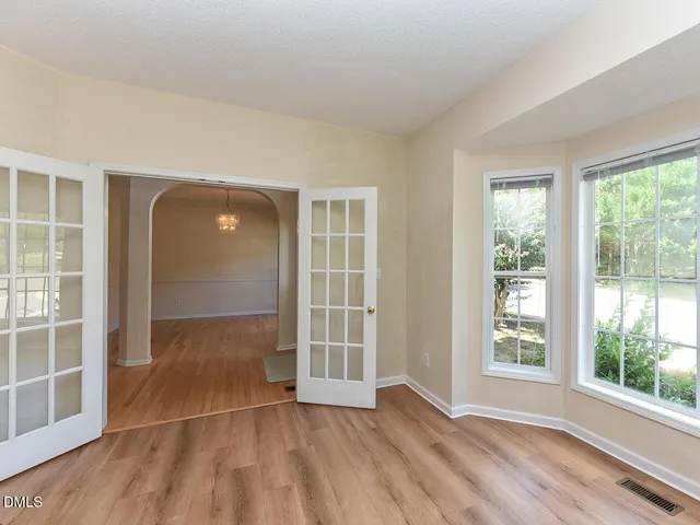 an empty room with wooden floor and windows