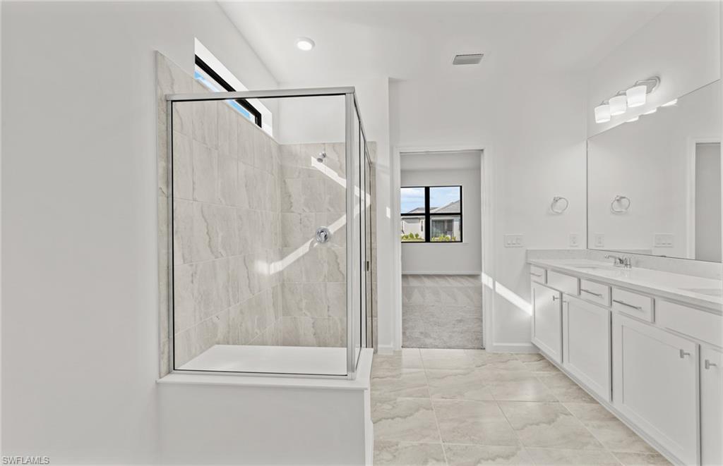 3922 East Hampton Circle Fort Myers, FL 33905 - Photo 16 of 24 a bathroom with a double vanity sink a large mirror and a bathtub