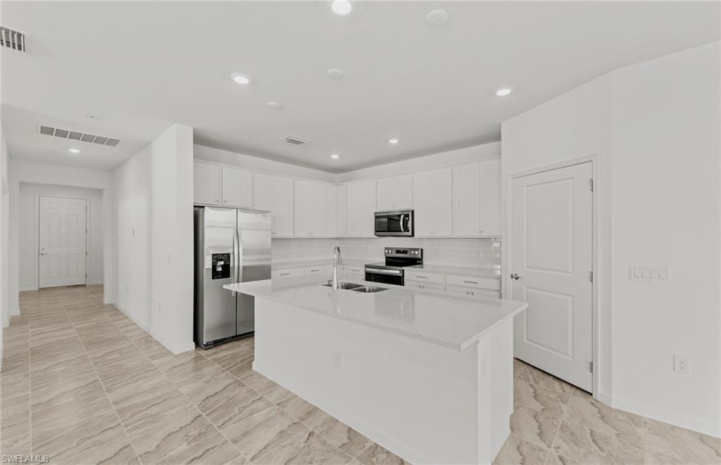 3922 East Hampton Circle Fort Myers, FL 33905 - Photo 4 of 24 a kitchen that has a lot of white cabinets and stainless steel appliances