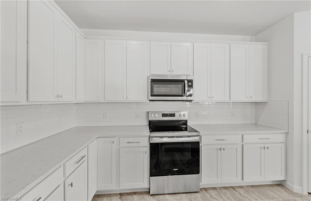 3922 East Hampton Circle Fort Myers, FL 33905 - Photo 7 of 24 a kitchen with white cabinets and stainless steel appliances