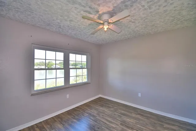 an empty room with wooden floor fan and windows