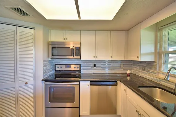 a kitchen with stainless steel appliances granite countertop a sink and a microwave