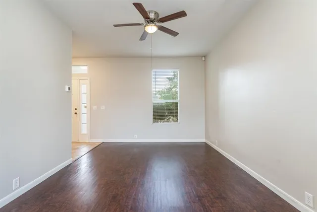an empty room with wooden floor fan and windows
