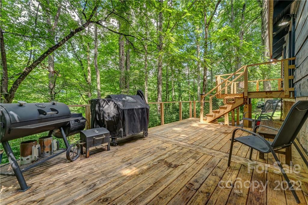 1305 Old Balsam Road Waynesville, NC 28786 - Photo 11 of 42 a view of a roof deck with table and chairs a barbeque with wooden floor and fence