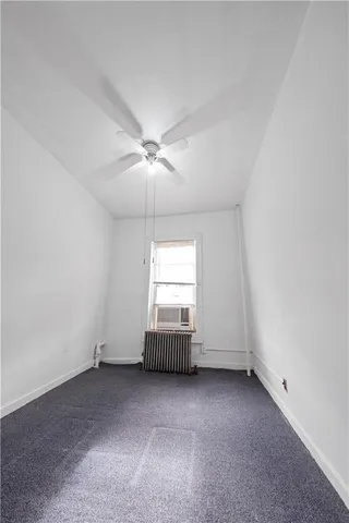 an empty room with a chandelier fan and windows