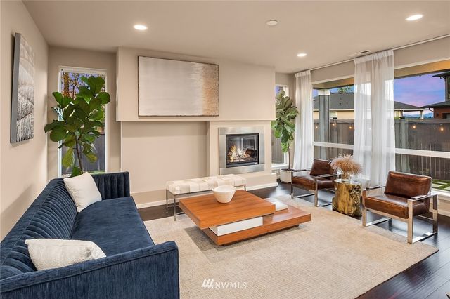 a living room with couches chairs and kitchen view with wooden floor