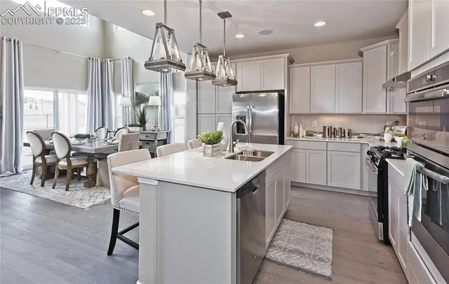 a kitchen with stainless steel appliances kitchen island a table chairs in it and wooden floors