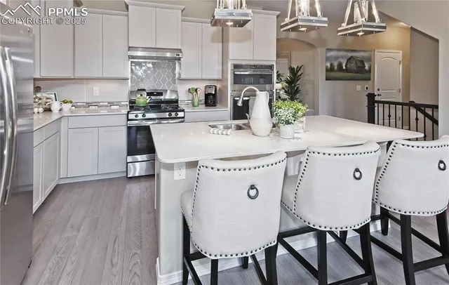 a kitchen with stainless steel appliances kitchen island granite countertop a table chairs and a refrigerator