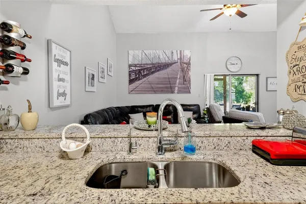a kitchen with granite countertop a sink stainless steel appliances and white cabinets