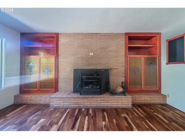 a view of an empty room with window and wooden floor