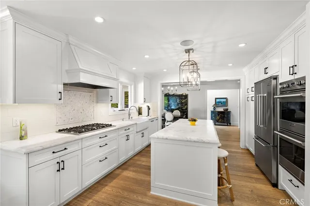 a kitchen with stainless steel appliances kitchen island granite countertop a sink and dishwasher a stove top oven with wooden floor