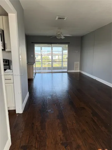a view of empty room with wooden floor and fan