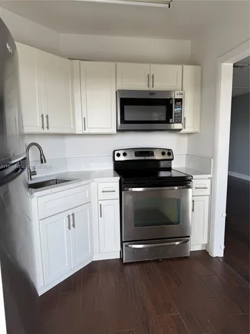 a kitchen with white cabinets stainless steel appliances and wooden floor