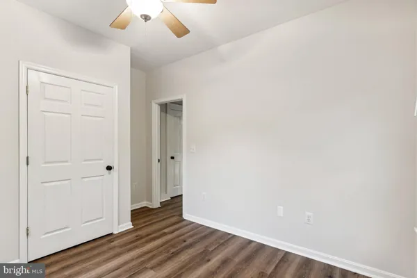 an empty room with wooden floor closet and windows