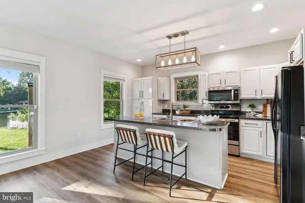 a kitchen with stainless steel appliances granite countertop a stove top oven a sink dishwasher a dining table and chairs with wooden floor