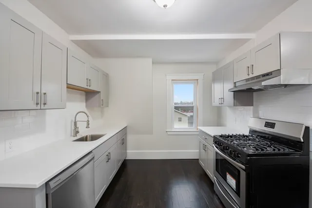a kitchen with granite countertop a sink stove and cabinets