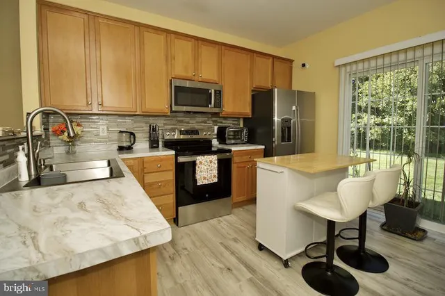 a kitchen with stainless steel appliances granite countertop a stove top oven a sink dishwasher and white cabinets with wooden floor