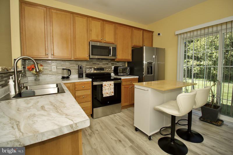 162 Lexington Place Dover, DE 19901 - Photo 13 of 48 a kitchen with stainless steel appliances granite countertop a stove top oven a sink dishwasher and white cabinets with wooden floor