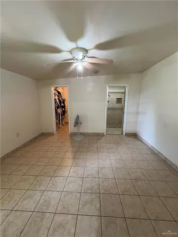 a view of an empty room and chandelier fan