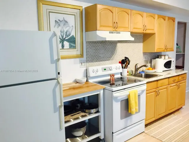 a kitchen with stainless steel appliances a white refrigerator a sink and a stove with white countertops