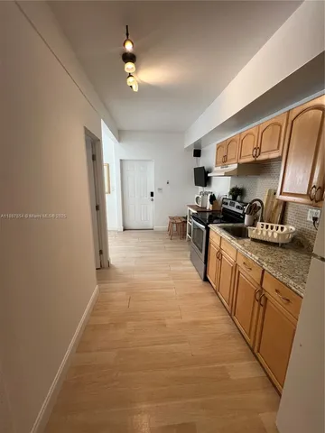 a large kitchen with stainless steel appliances a sink stove and cabinets