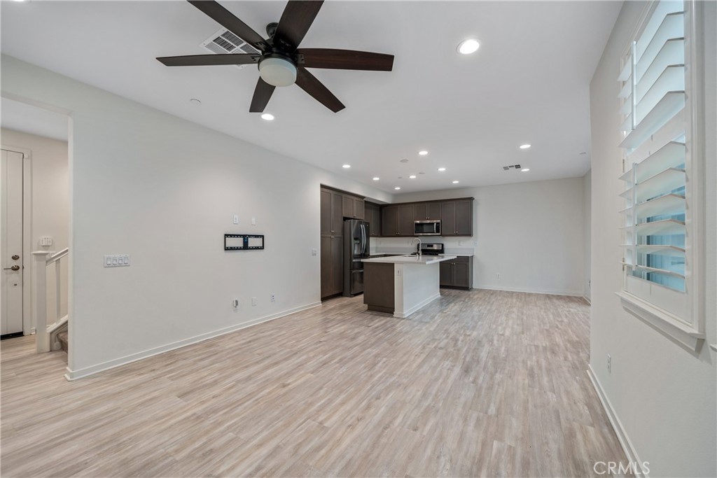 11082 Panoramic Drive Rancho Cucamonga, CA 91730 - Photo 7 of 48 a big room with wooden floor a ceiling fan and kitchen space