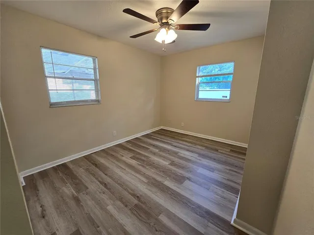 a view of a room with wooden floor and a ceiling fan