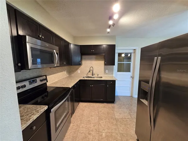 a kitchen with stainless steel appliances granite countertop a stove refrigerator and microwave