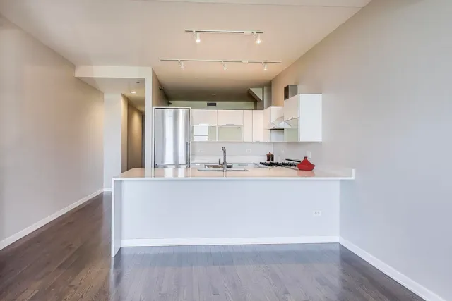 a large white kitchen with kitchen island a sink stainless steel appliances and cabinets