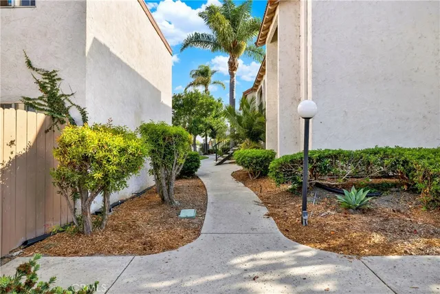 a view of a white house with a big yard plants and large trees