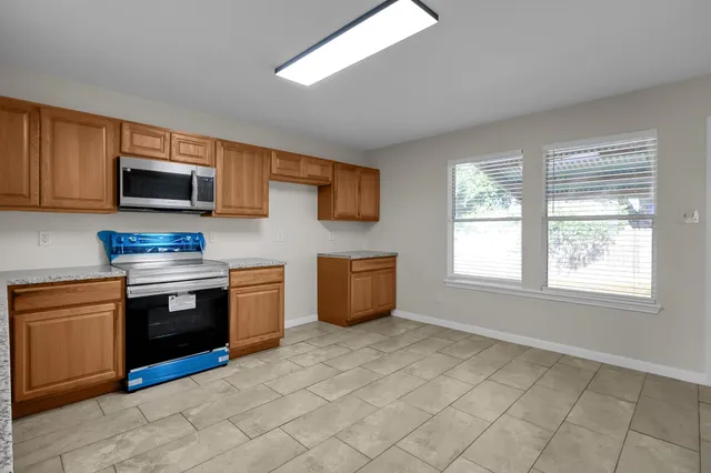 a kitchen with stainless steel appliances granite countertop a stove top oven a sink dishwasher and a microwave oven on the blue kitchen countertops