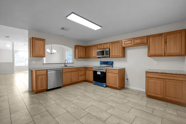 a kitchen with granite countertop a sink cabinets and stainless steel appliances