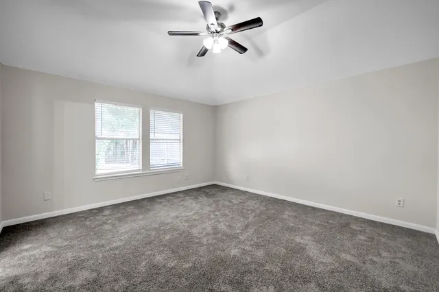 an empty room with windows and fan