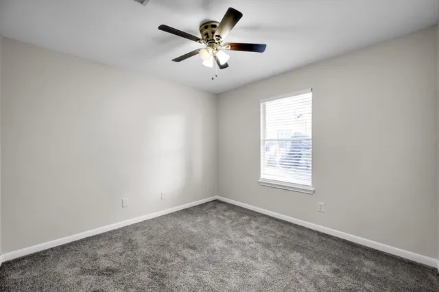 an empty room with a window and a fan