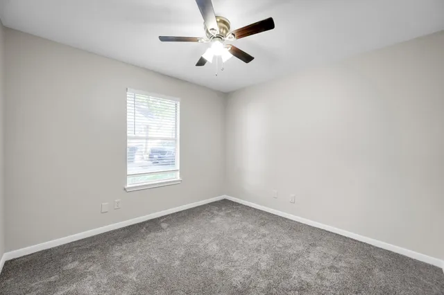 an empty room with a window and a fan