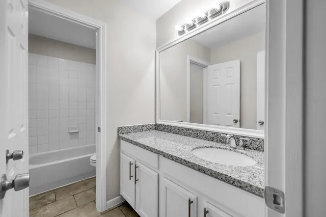 a bathroom with a granite countertop sink mirror and a bathtub