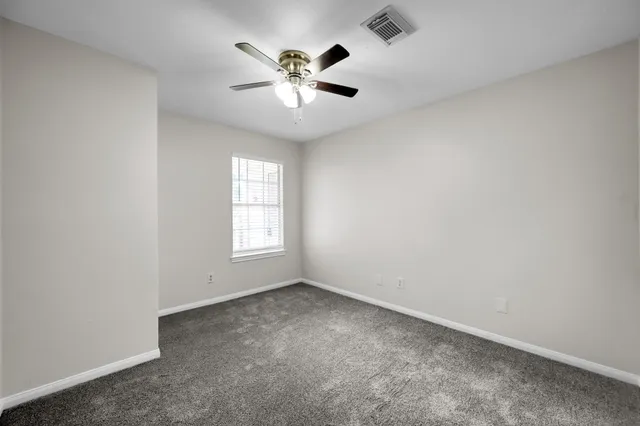 an empty room with chandelier fan and windows